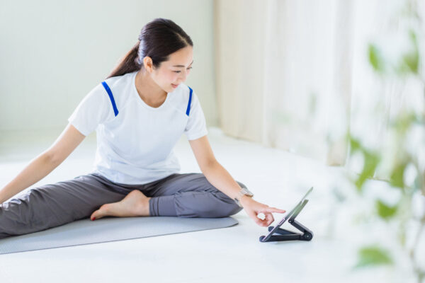 ヨガをしながらタブレットを操作する女性の写真