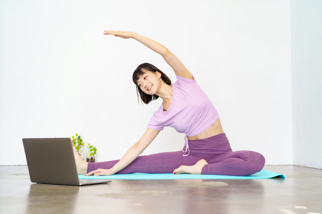 パソコンを開きながらヨガをする女性の写真